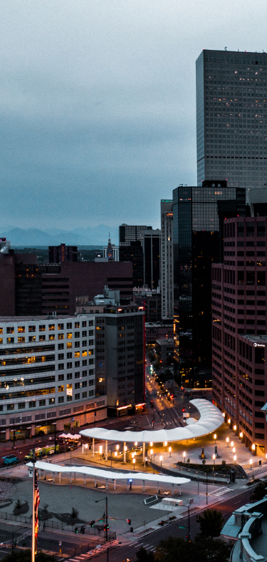 Modern living room with a kitchen, large windows, and various seating areas.