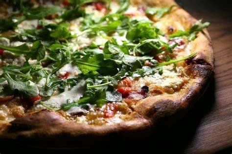A pizza with lots of toppings is sitting on a wooden table.