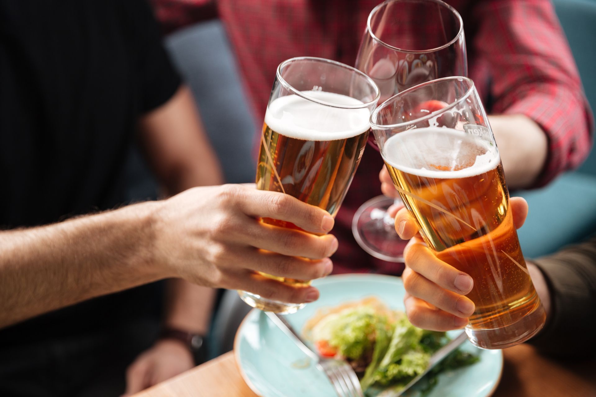 A group of people are toasting with beer and wine glasses.