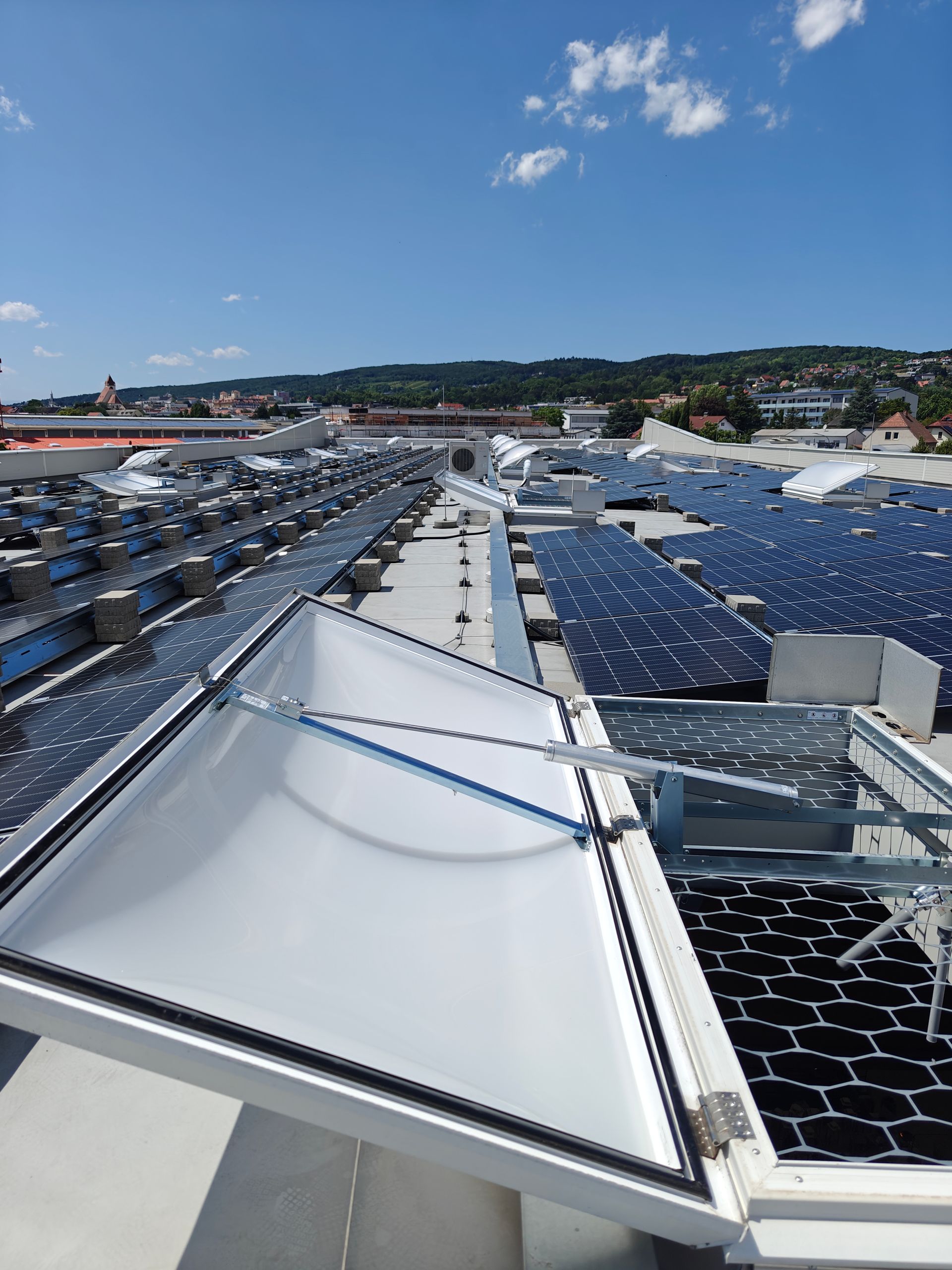 Solarpaneele auf dem Dach mit großem Oberlicht, blauer Himmel im Hintergrund.