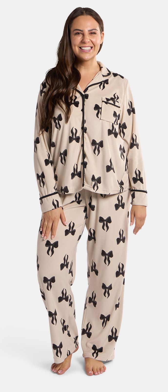 Woman wearing beige pajama set with black bow pattern.