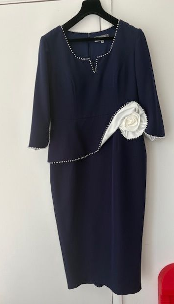Navy blue dress with white embellishments on a hanger.