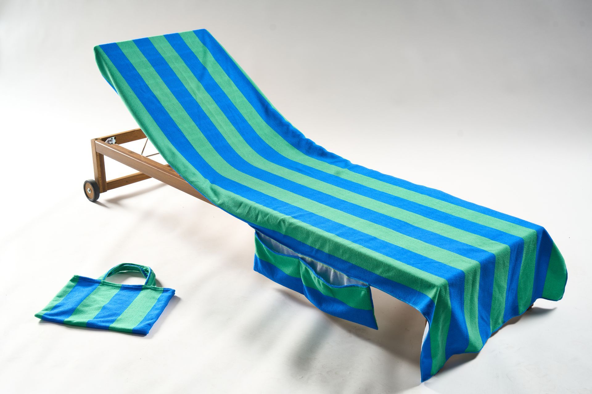 Beach chair with blue and green striped towel and matching tote bag.