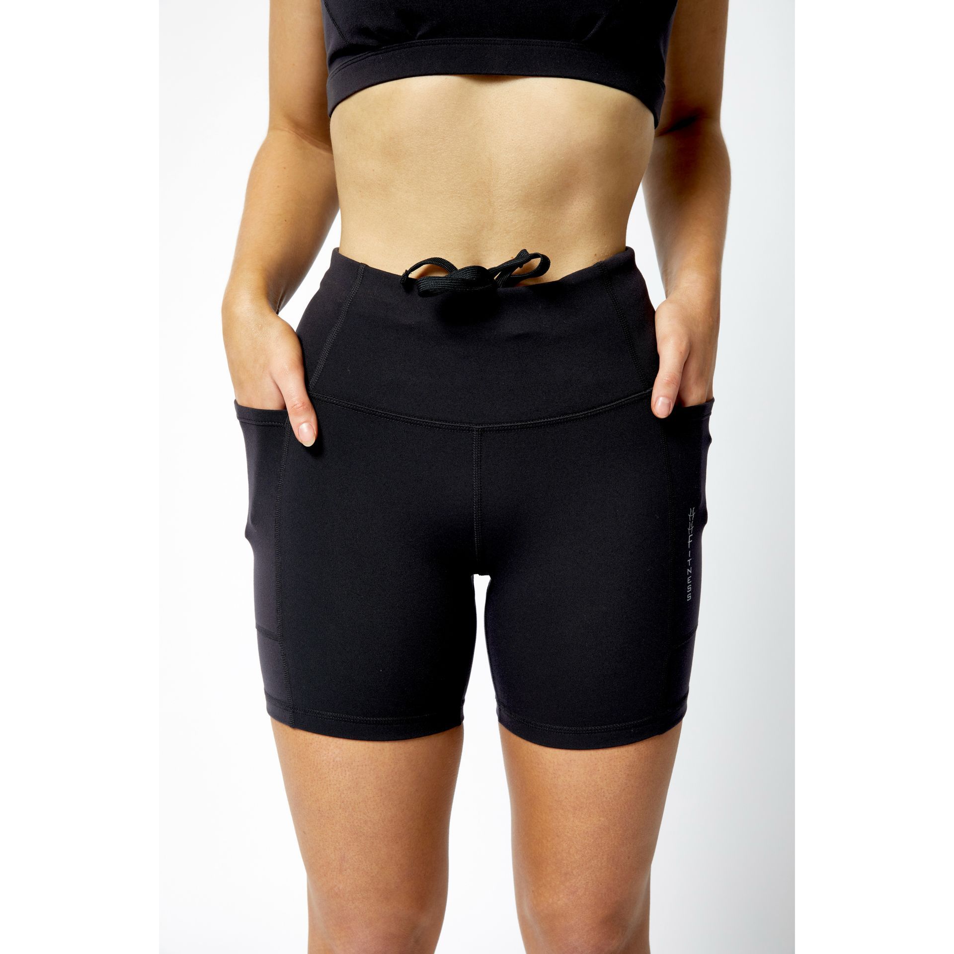 lady wearing 8 inch Happy Healthy Fitness shorts, with her hands in both large pockets