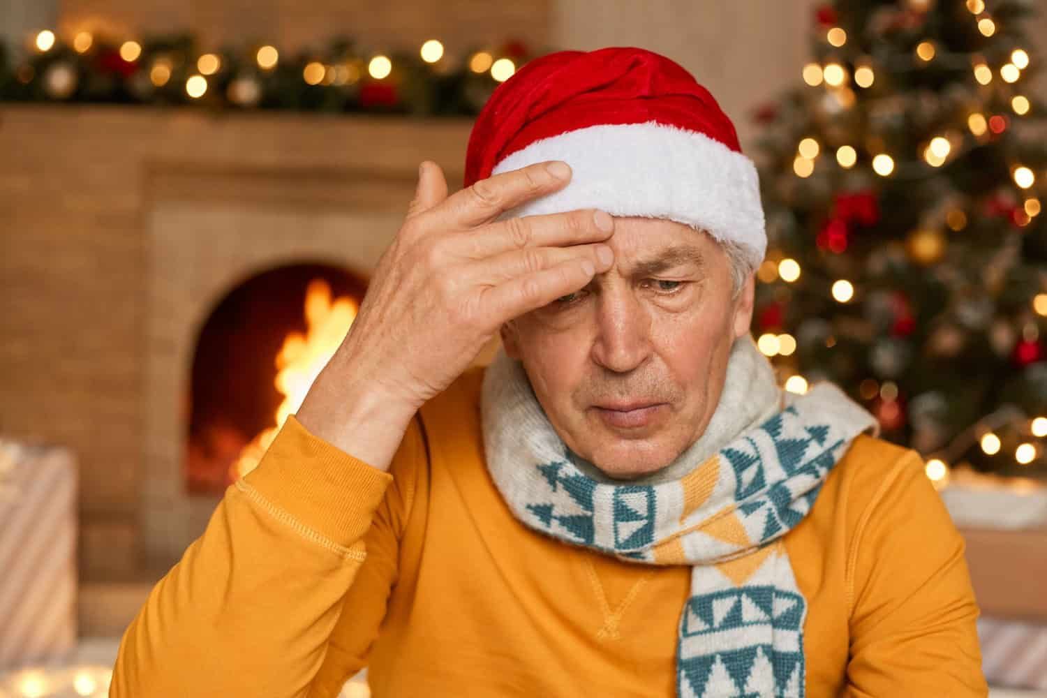 An old man wearing a Christmas hat looks worried