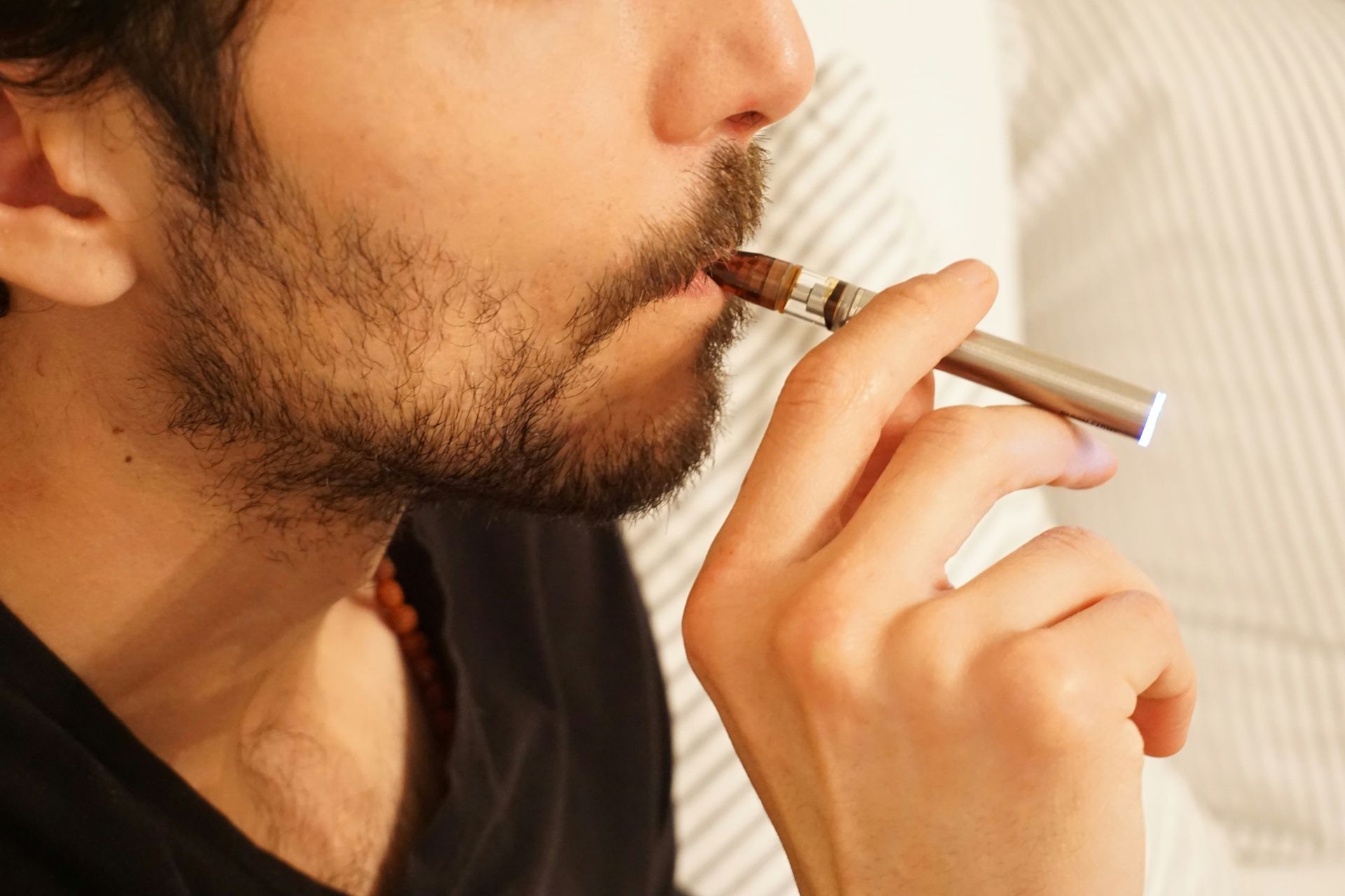 Close-up of a person using a vape pen, highlighting considerations for traveling with vapes.