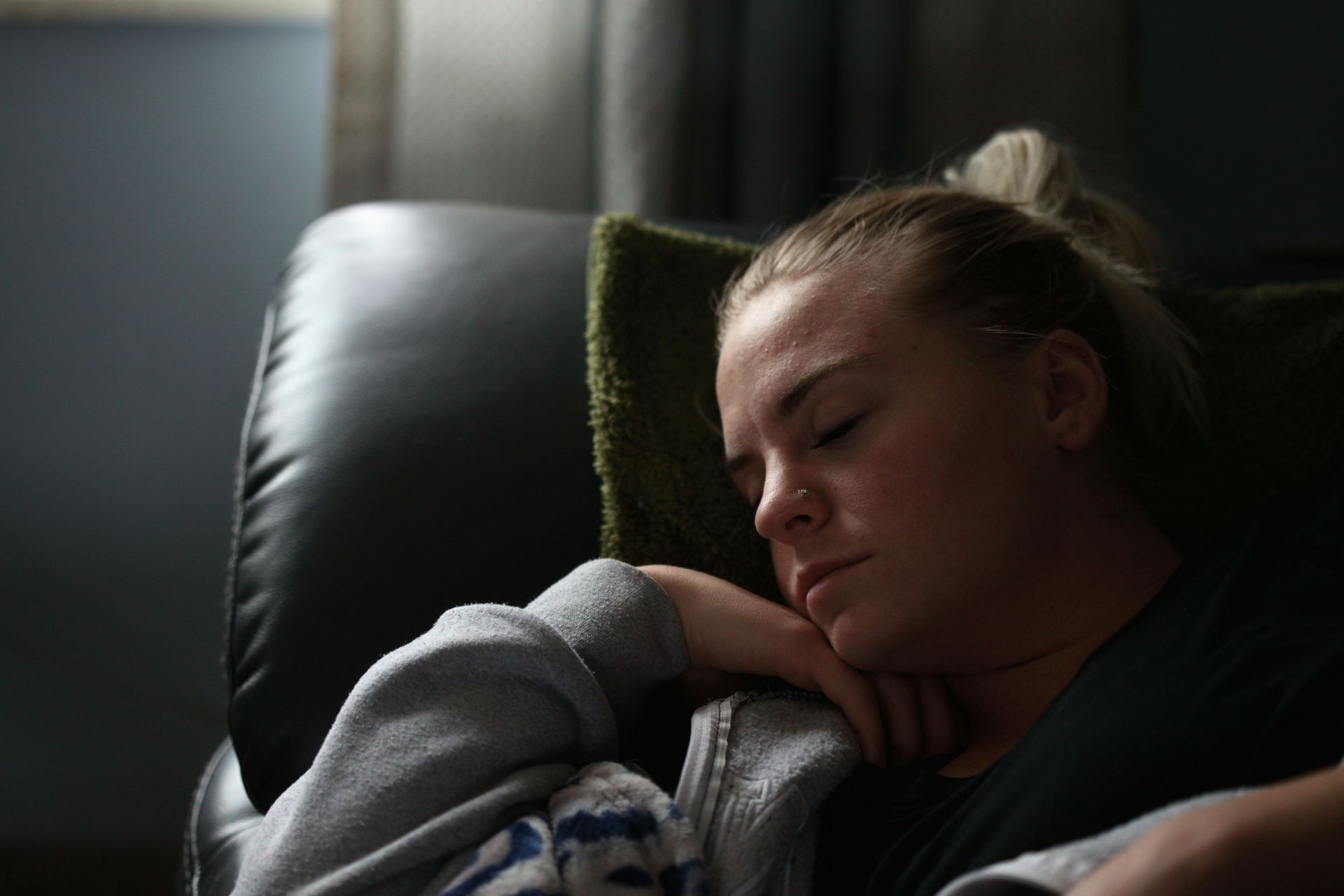 A woman resting on a couch with her eyes closed, appearing relaxed and comfortable.