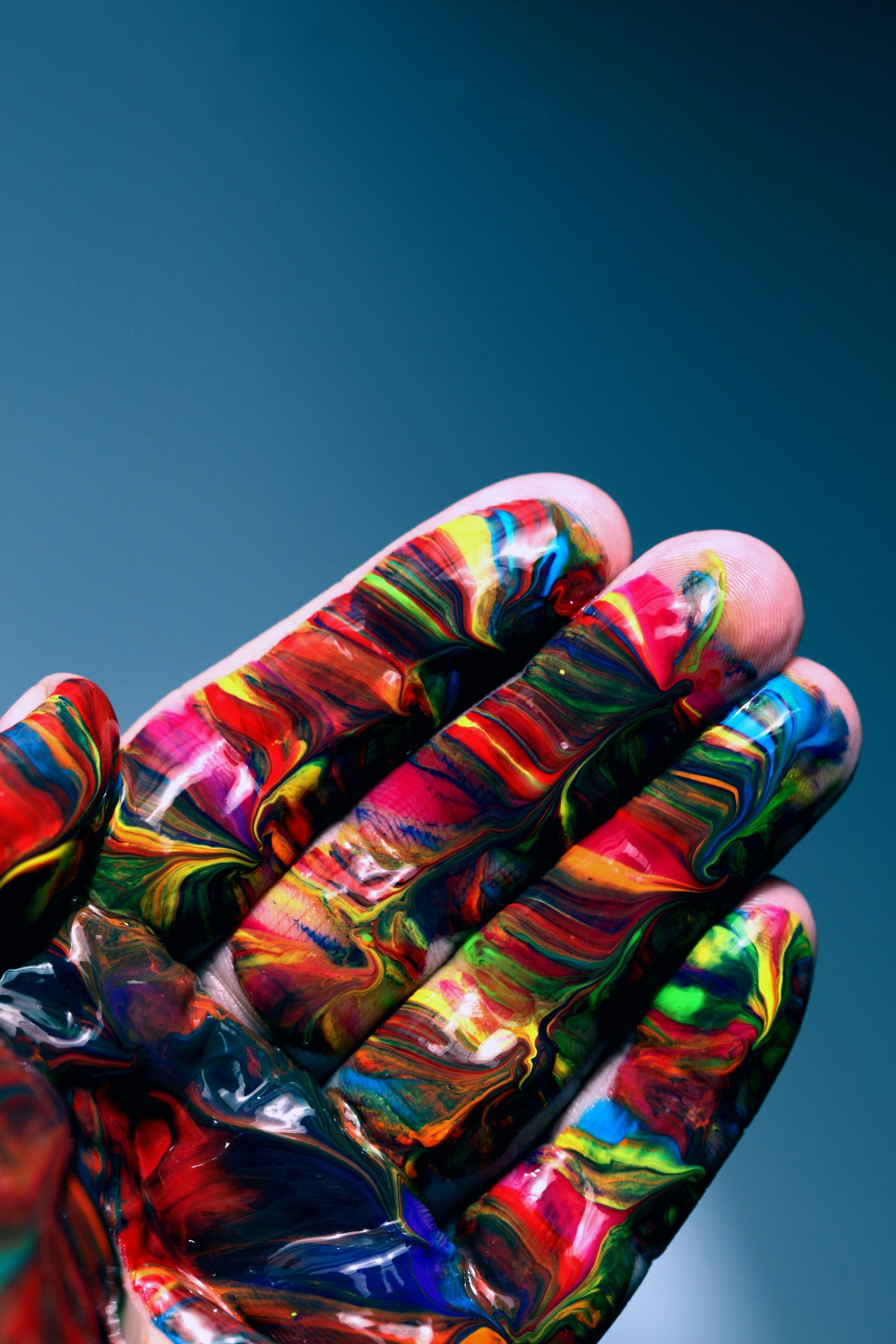 Close-up of a hand covered in vibrant, swirling paint colors, symbolizing the creative energy.