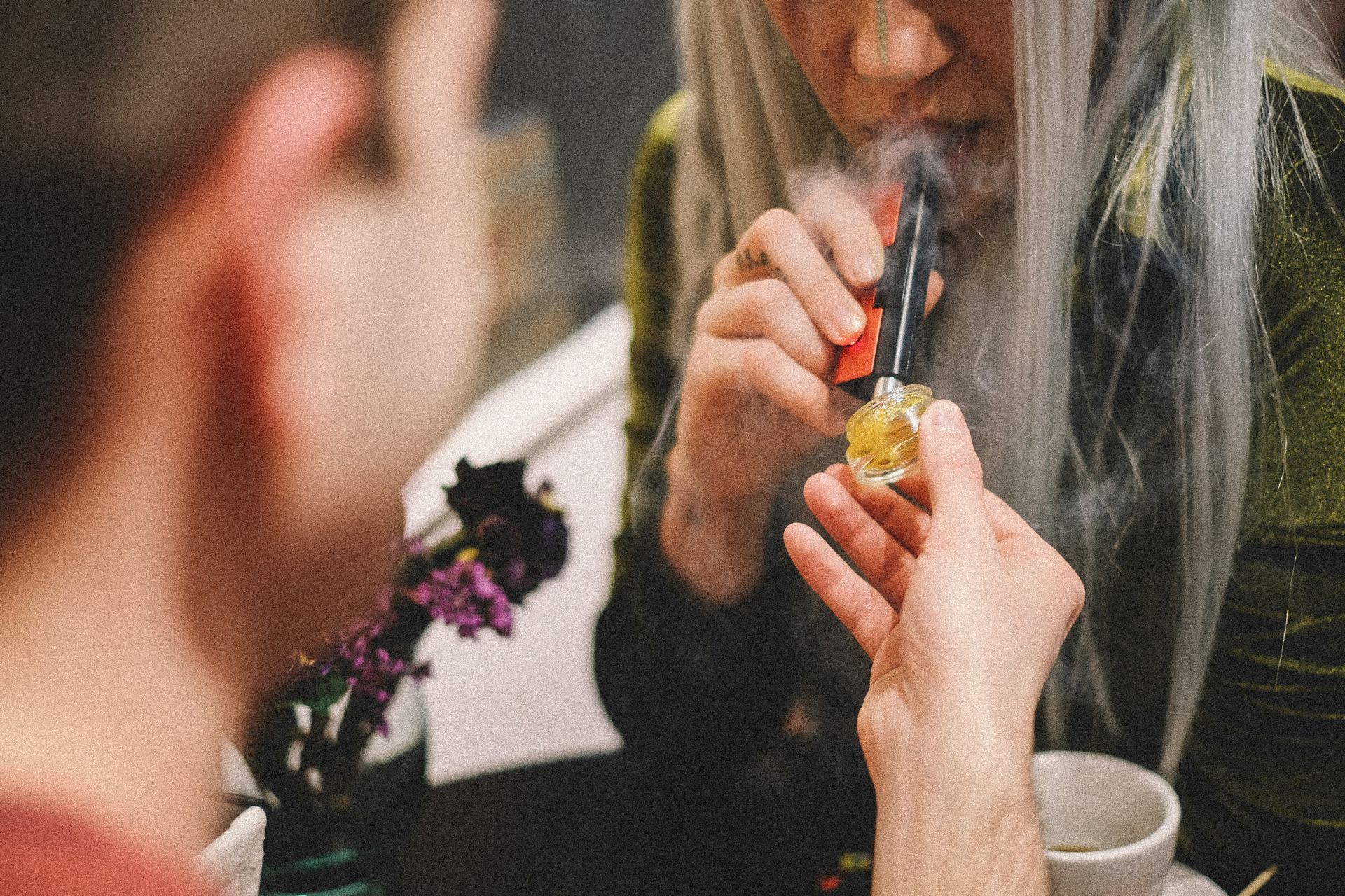 A person using a vape pen to consume cannabis concentrate which is a different consumption method.