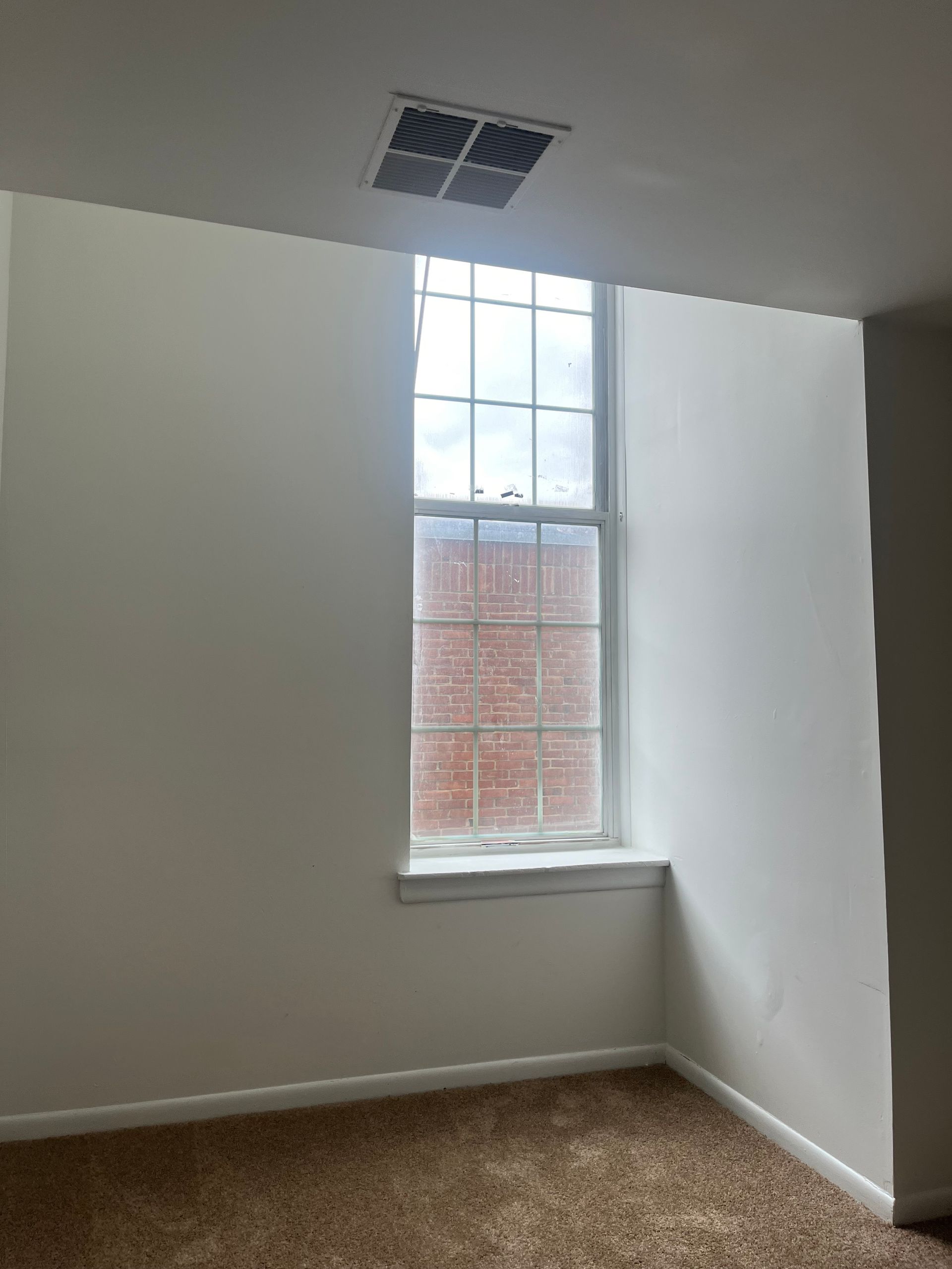An empty room with a window and a ceiling fan.