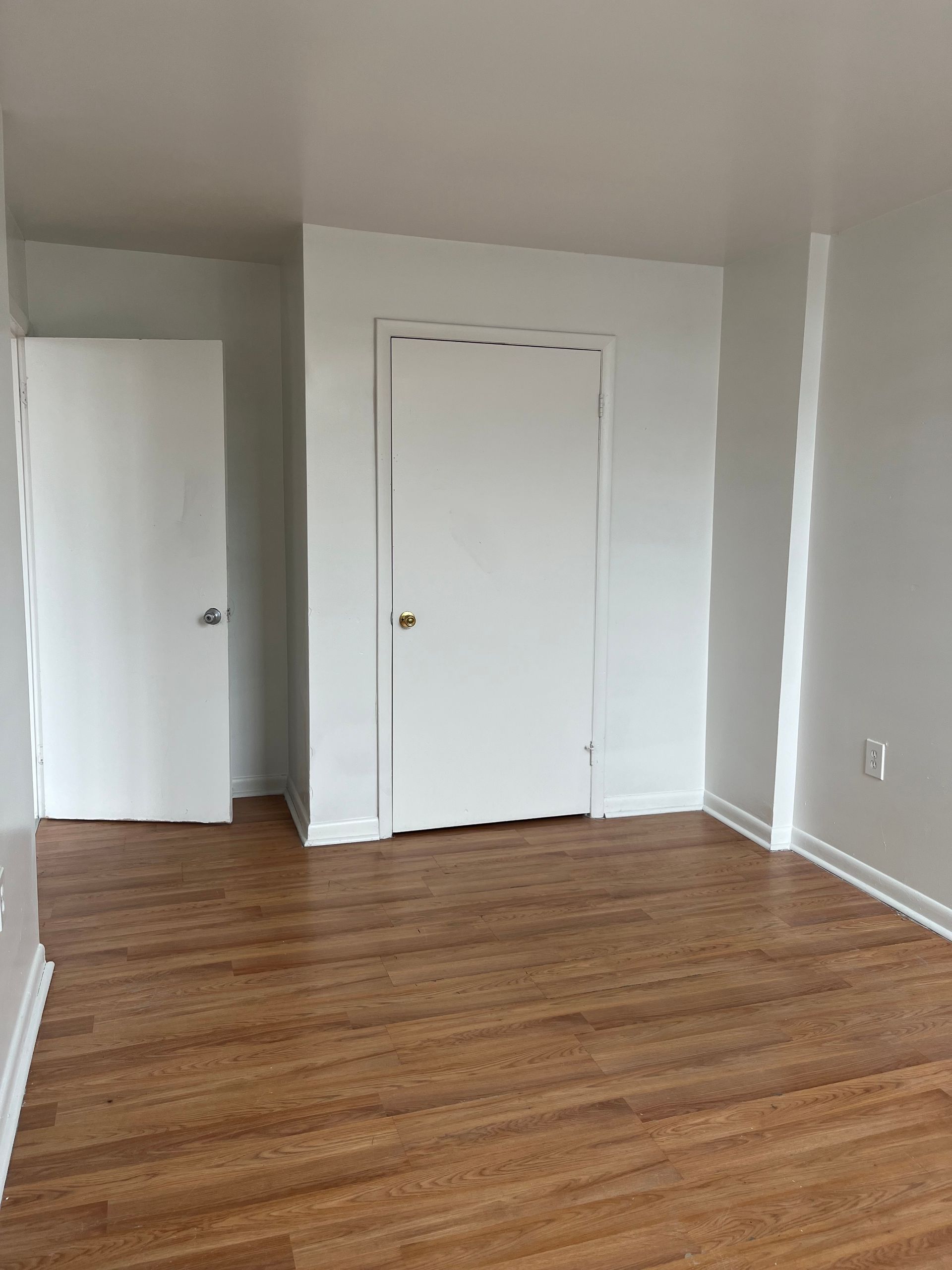 An empty room with hardwood floors and white walls