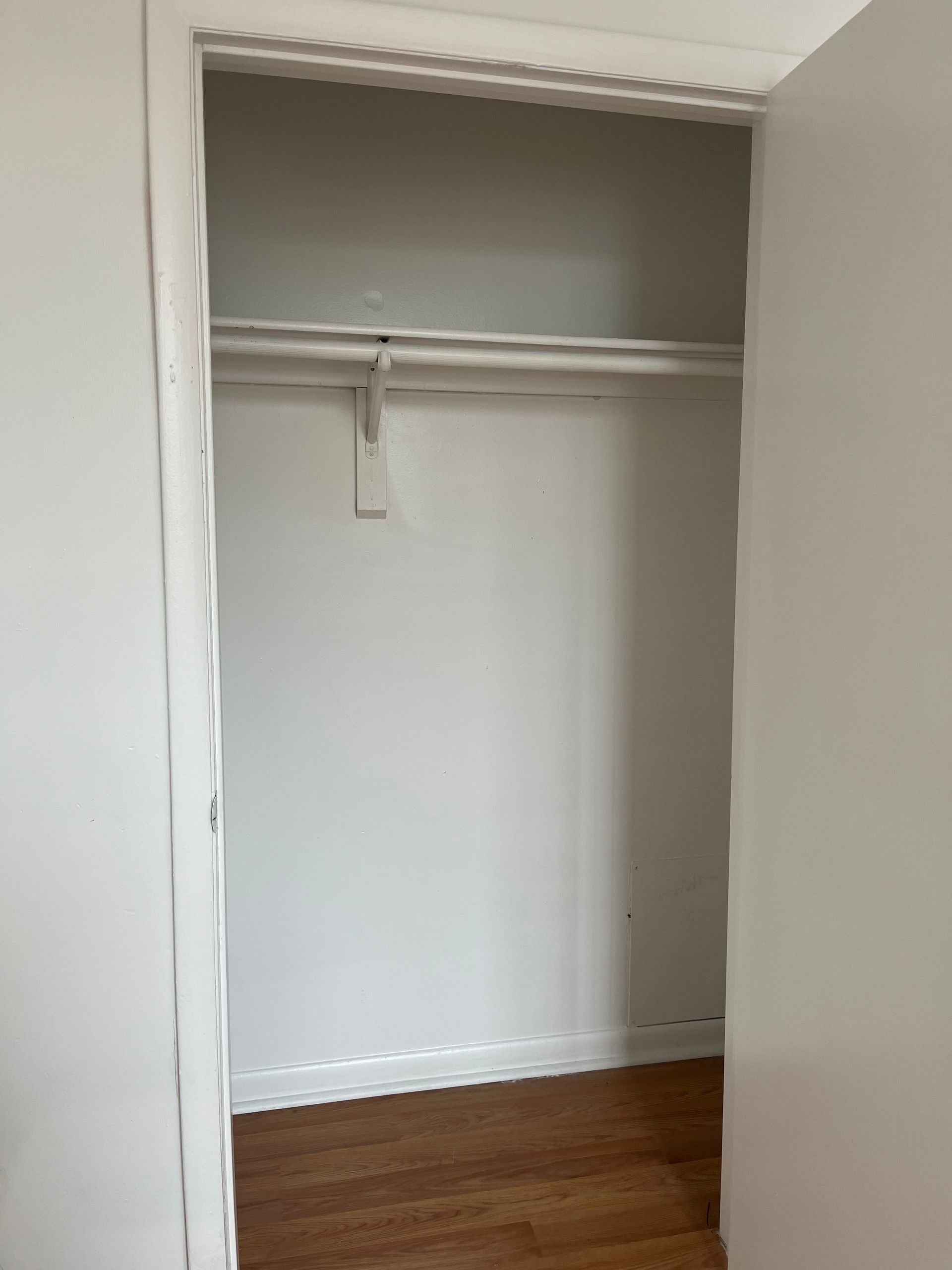 An empty closet with a wooden floor and white walls.