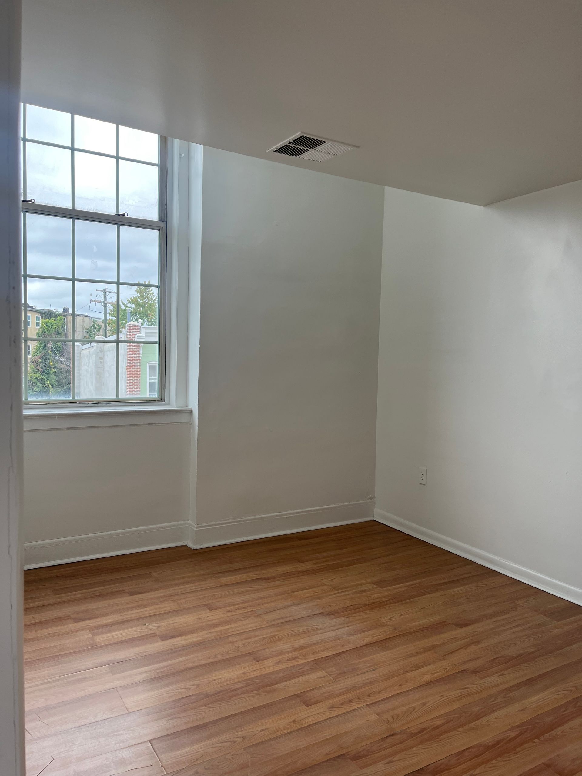 An empty room with hardwood floors and a window.