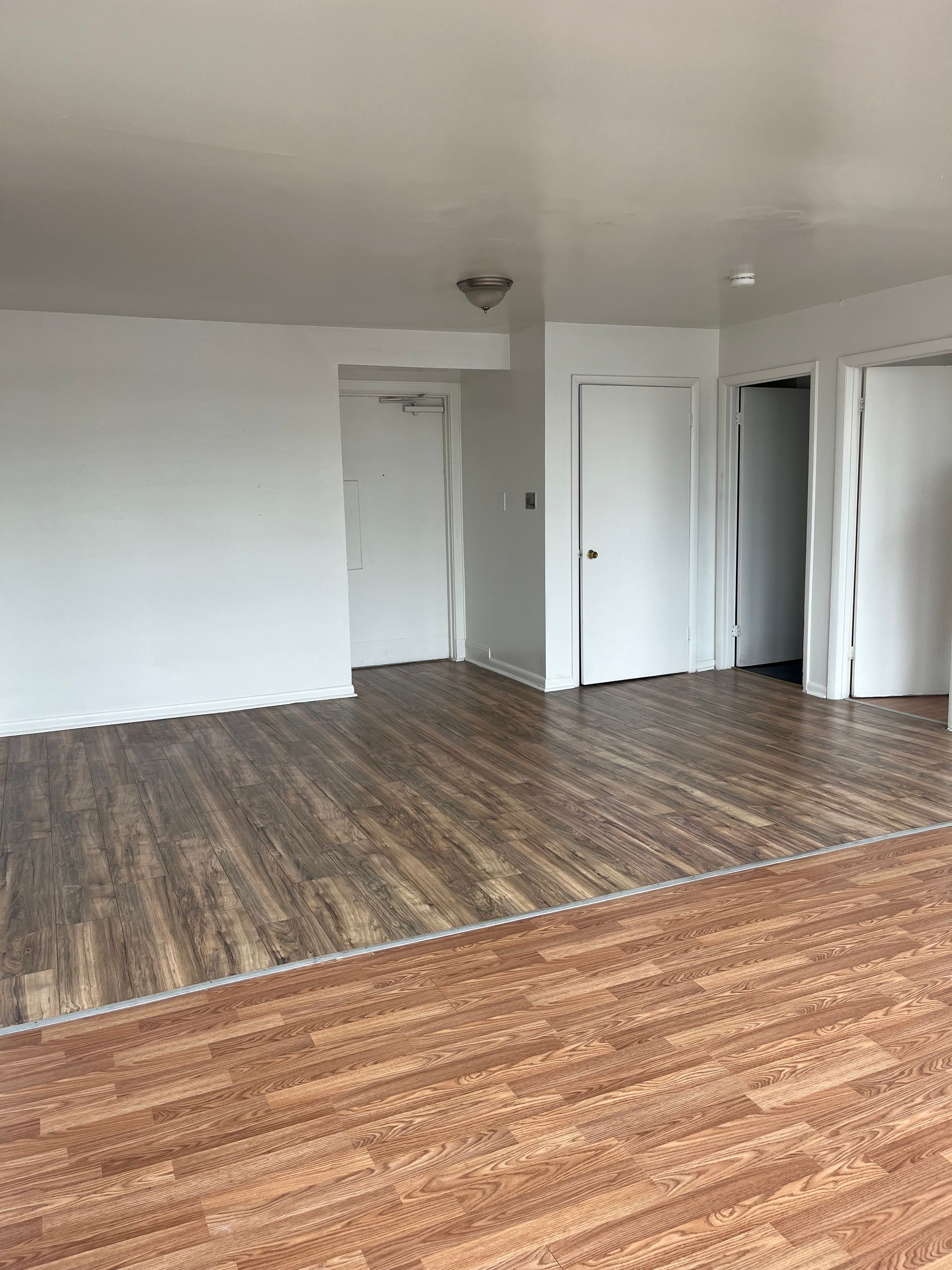 An empty living room with hardwood floors and white walls.