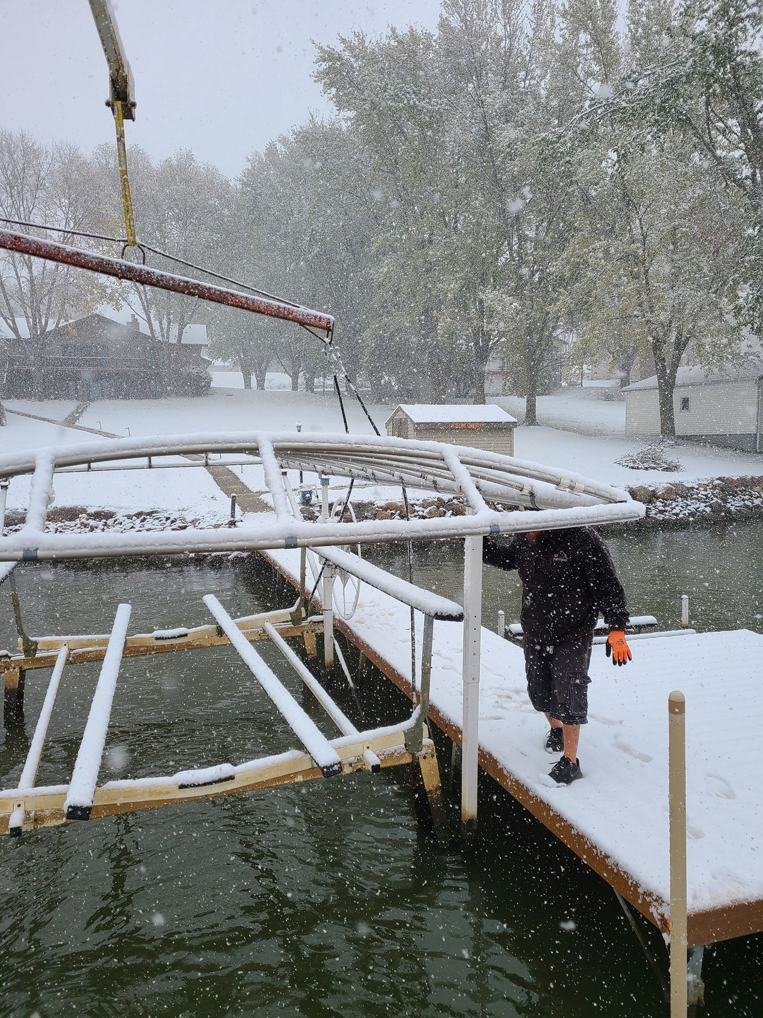 A man is standing on a dock in the snow near a body of water.