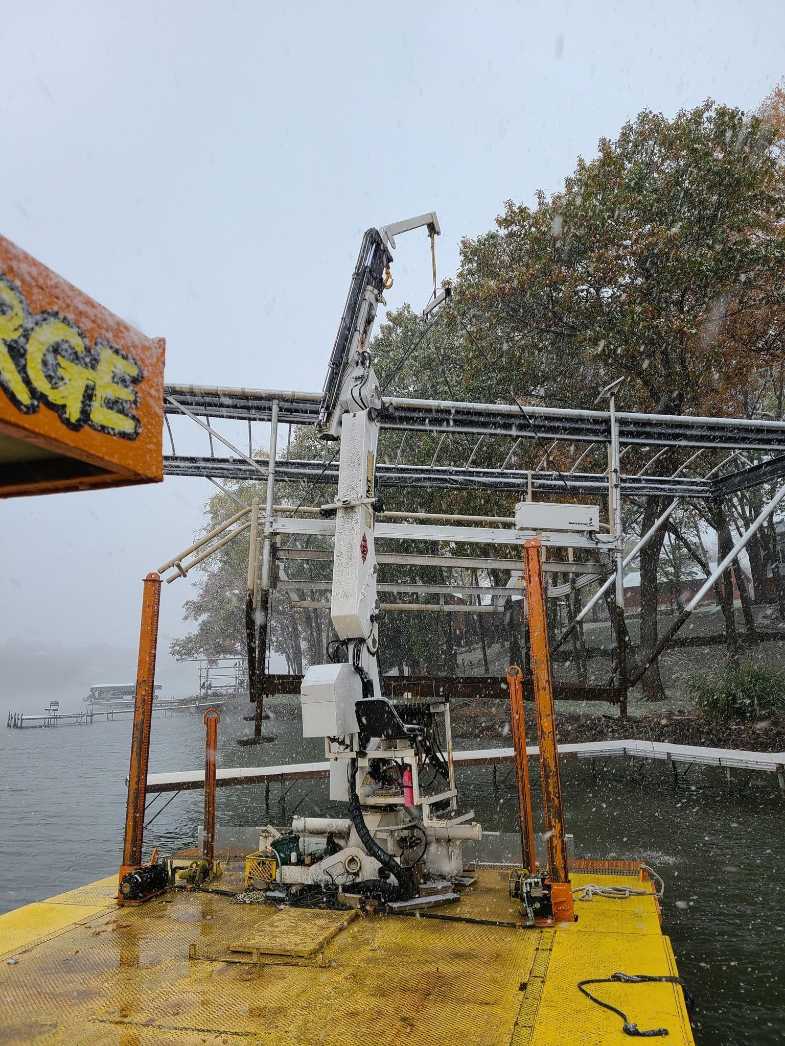 A crane is sitting on top of a yellow dock next to a body of water.