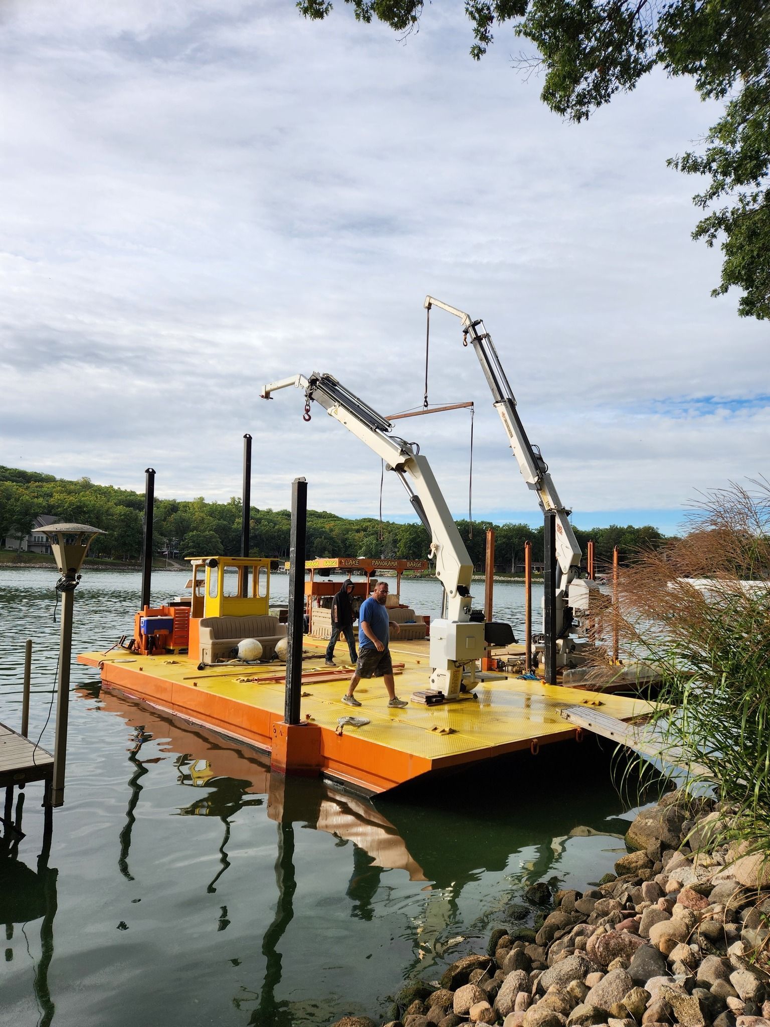 A man is standing on a dock next to a body of water.