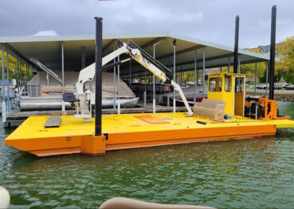 A yellow boat with a crane on it is docked at a dock.