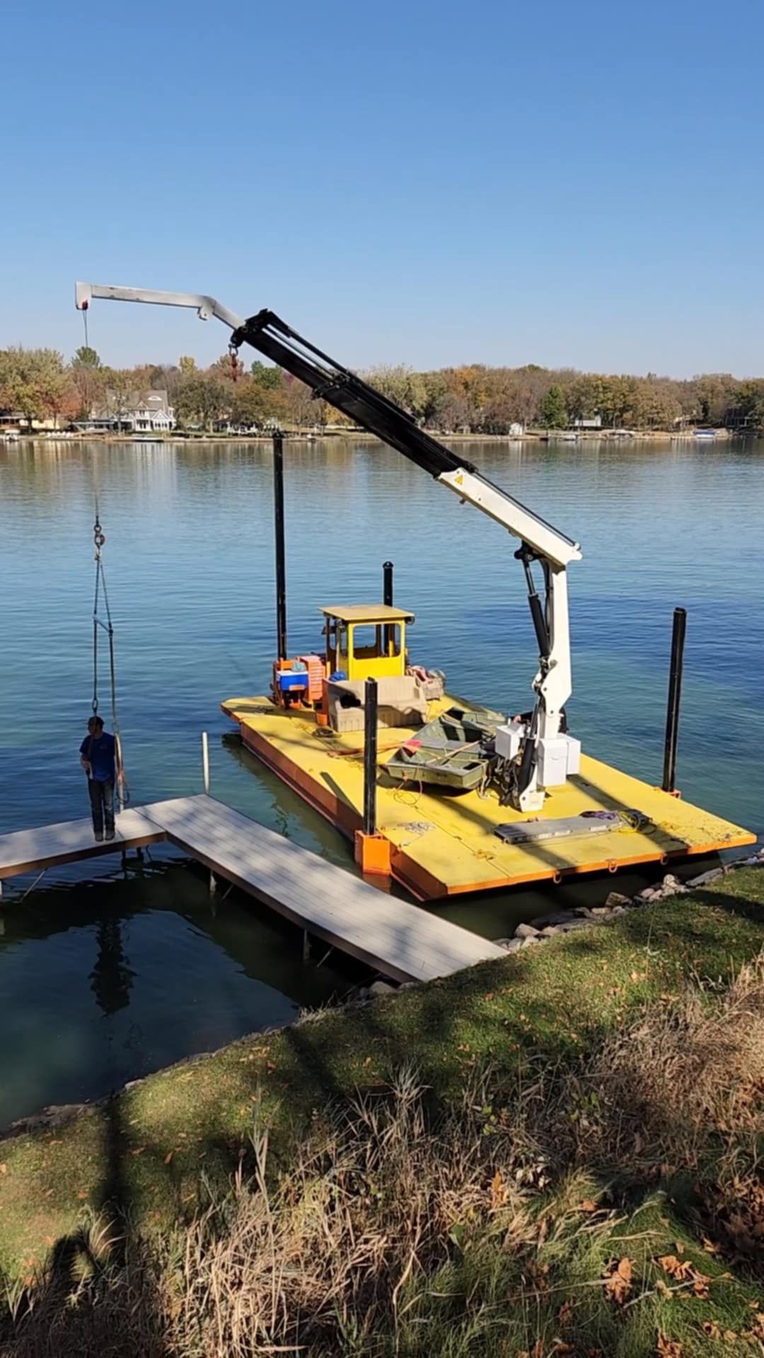 A boat with a crane attached to it is docked at a dock in the water.