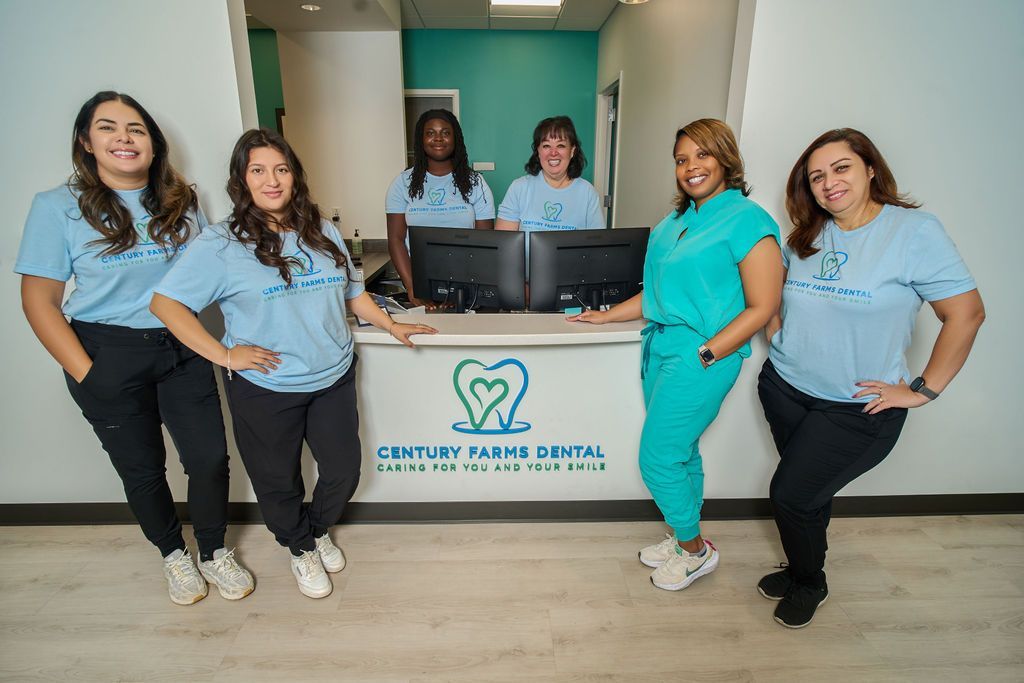 Century Park Dental staff poses near reception desk; turquoise, light blue, and black attire.