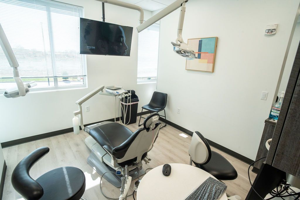 Dental exam room with chair, equipment, and mounted TV.