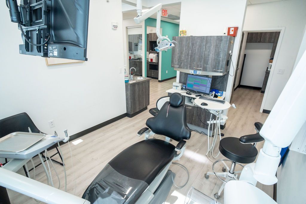 Dental office examining room with chair, equipment, and cabinets.