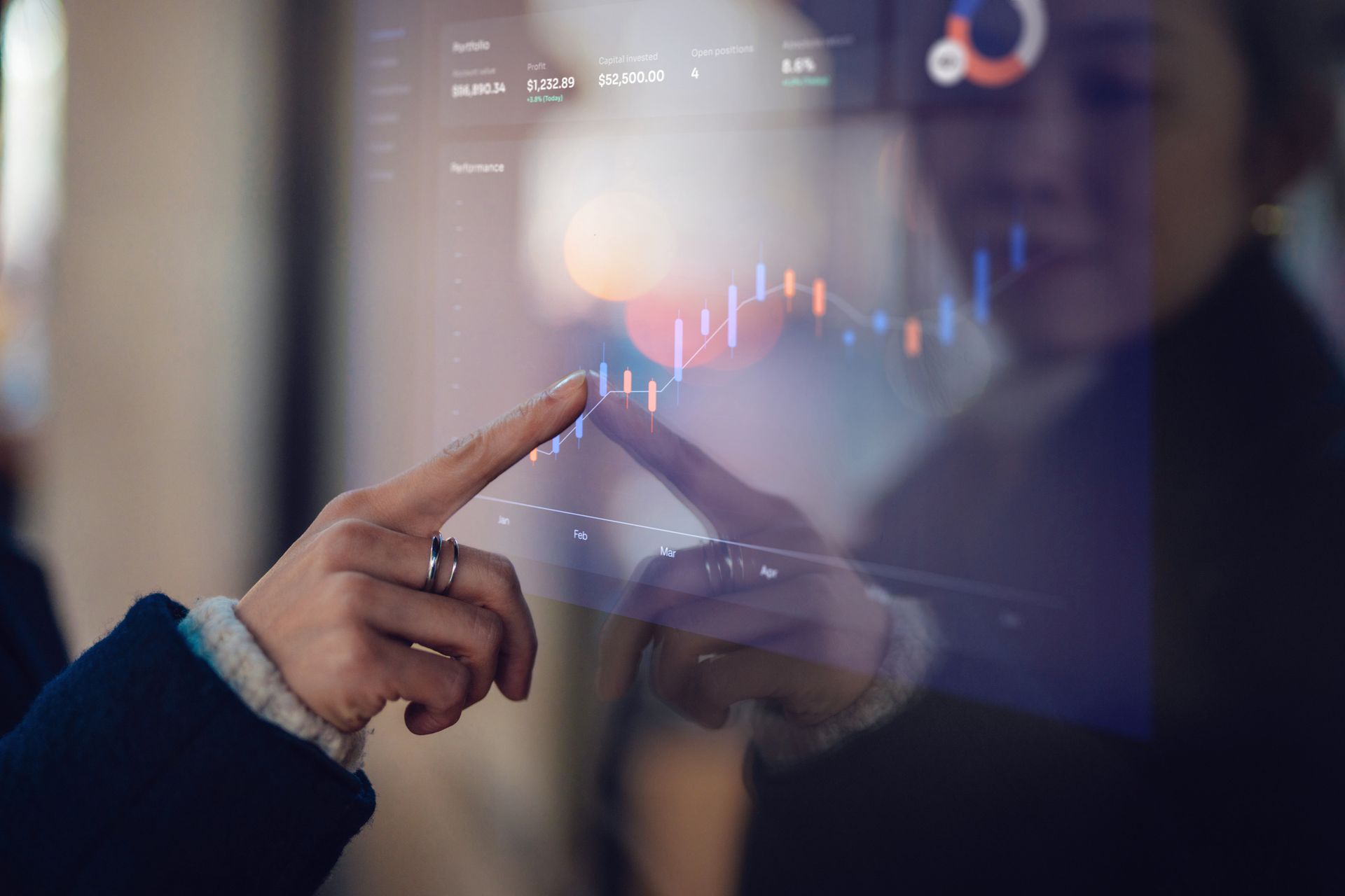 Hands pointing at a stock chart reflected on a glass surface, possibly interactive.