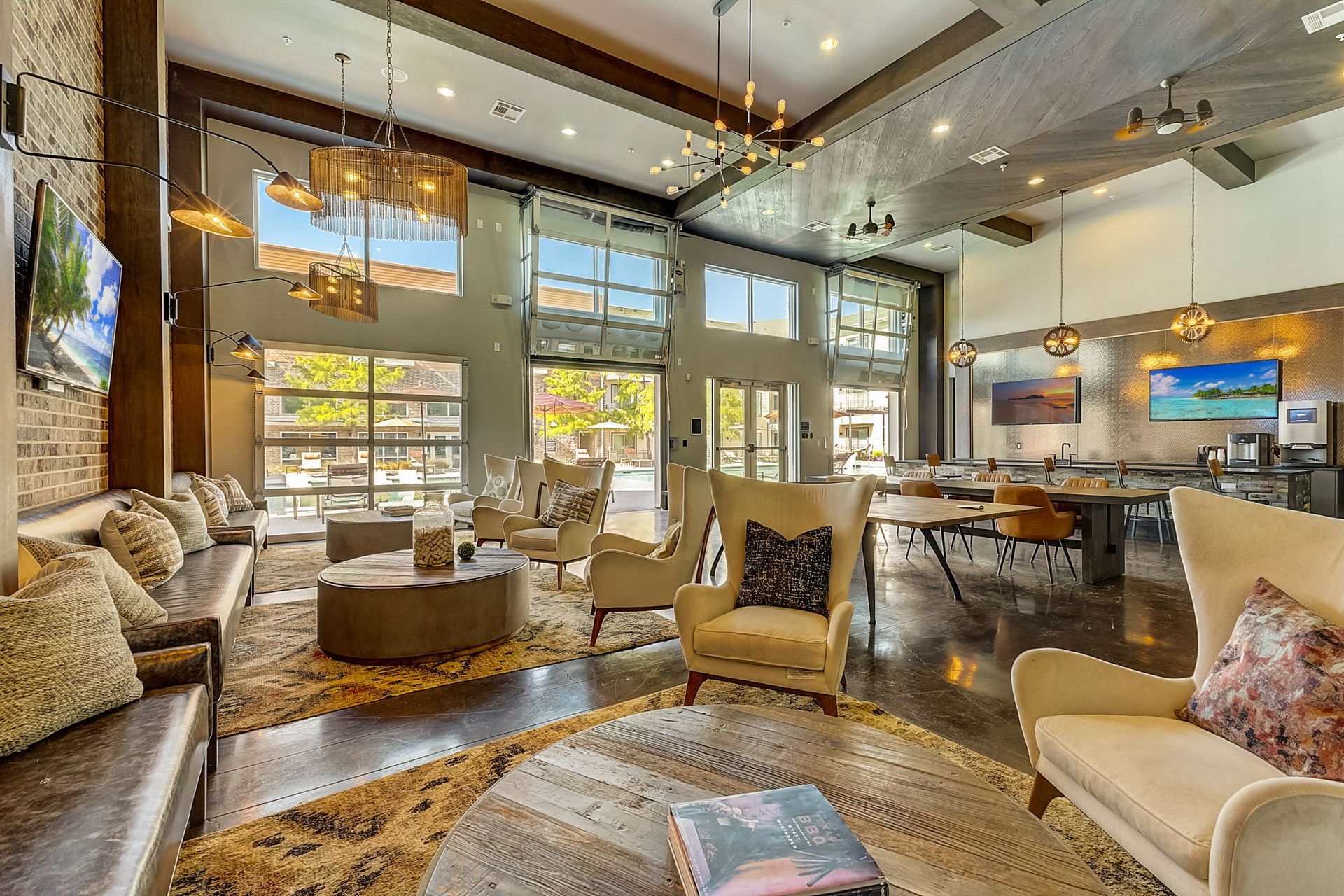Lobby with couches, armchairs, round coffee tables, and large windows. Warm lighting and modern decor create a welcoming space.