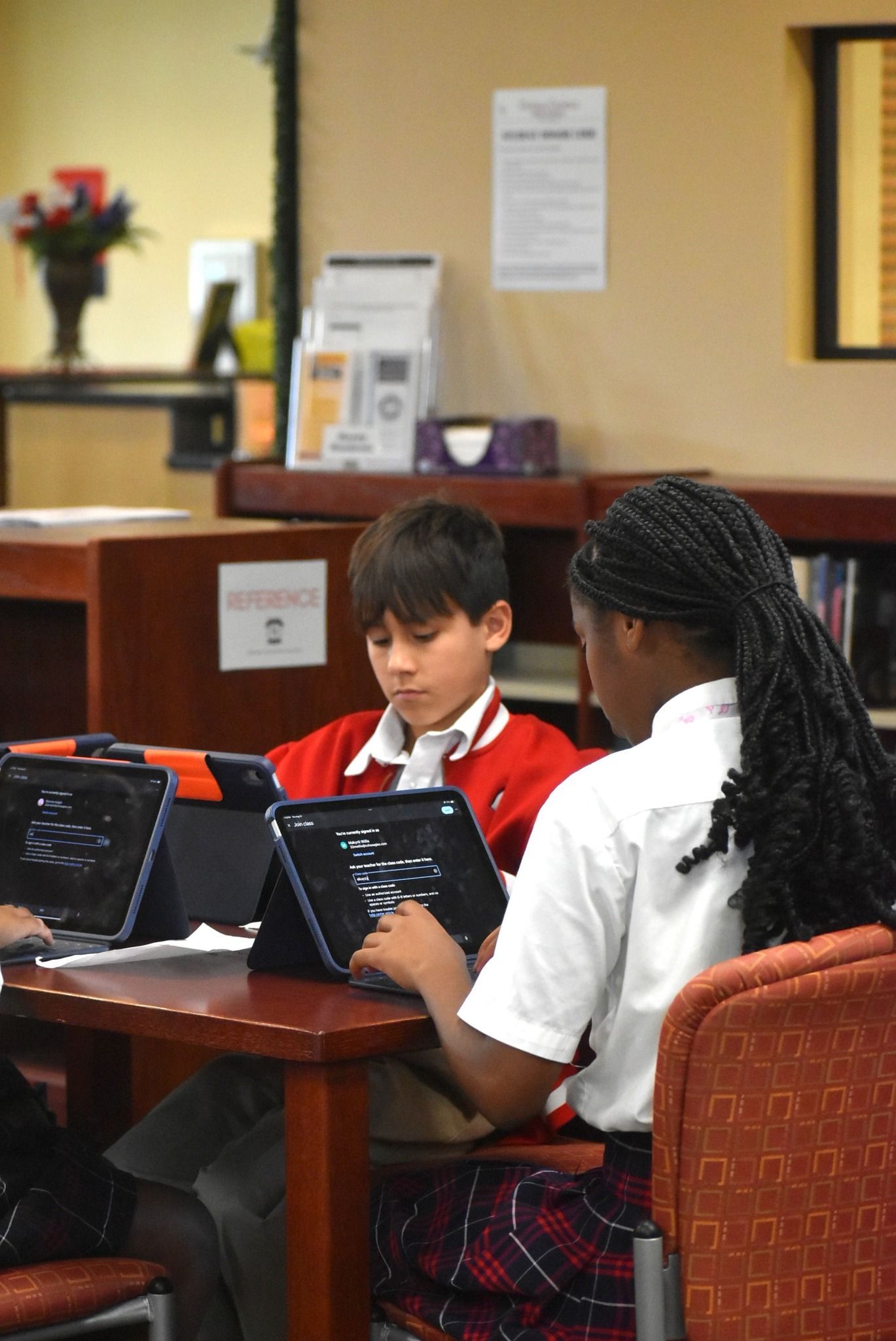 A boy sits at a desk with a tablet and a pencil