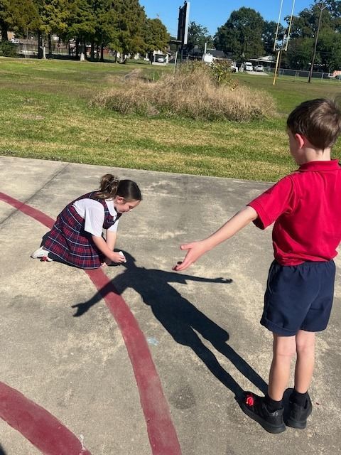A girl in a red shirt sits at a desk with a laptop