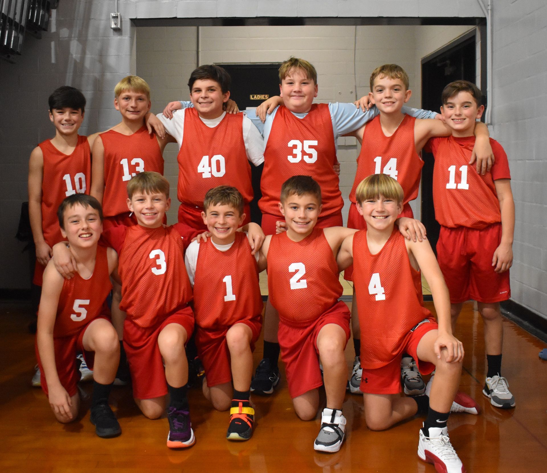 A group of young boys wearing red jerseys with numbers on them