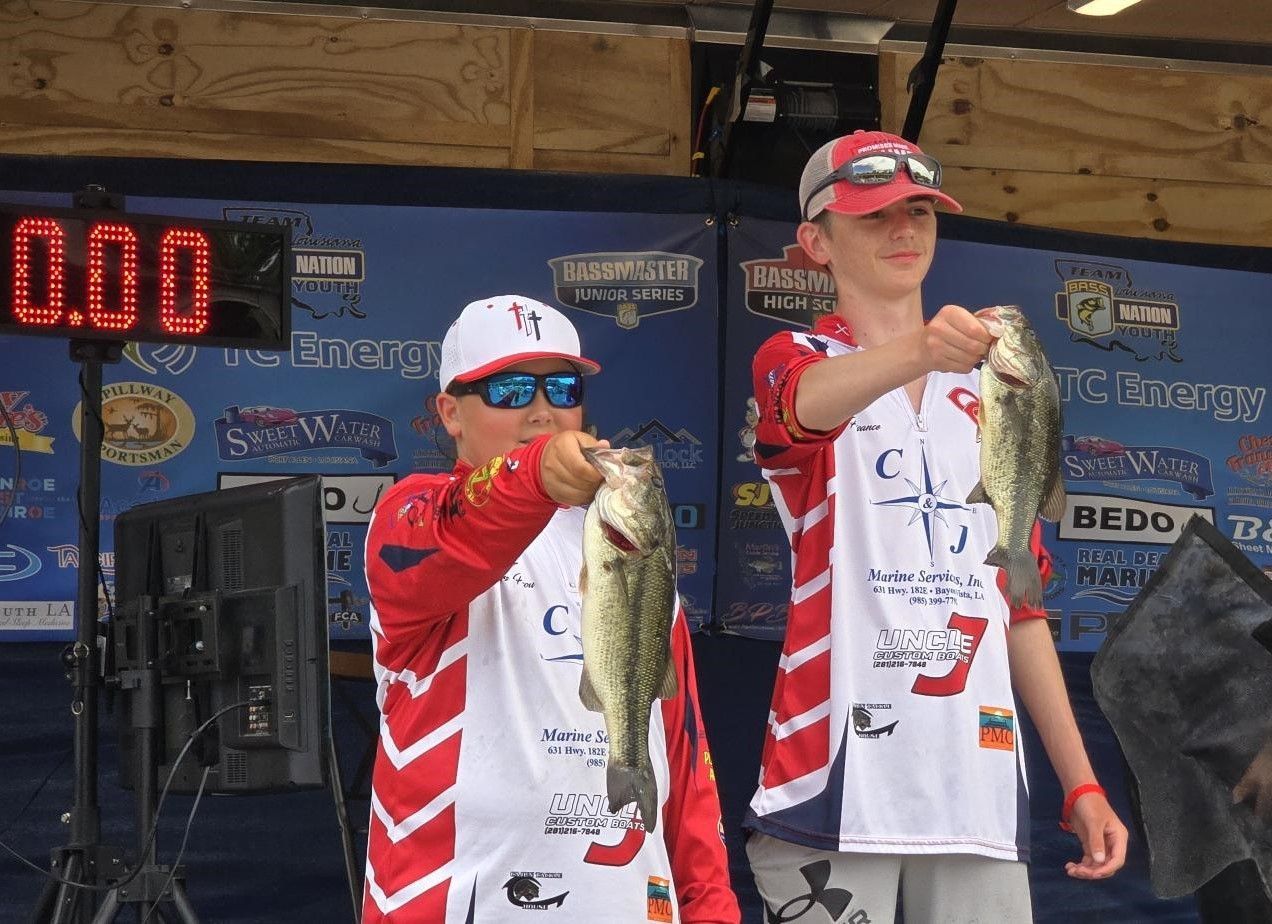 Two boys holding fish in front of a sign that says 0.00