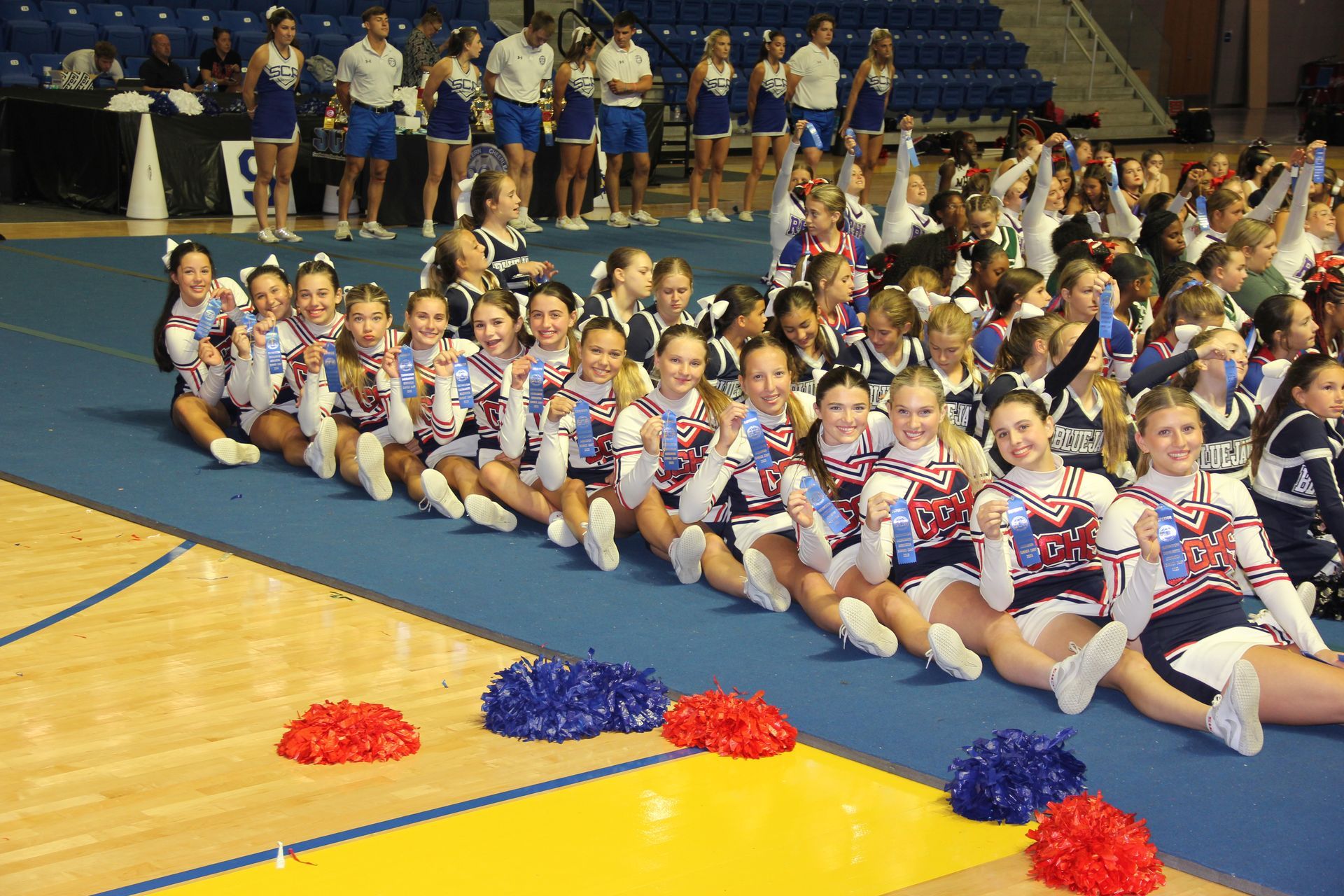 A group of cheerleaders are lined up on a gym floor