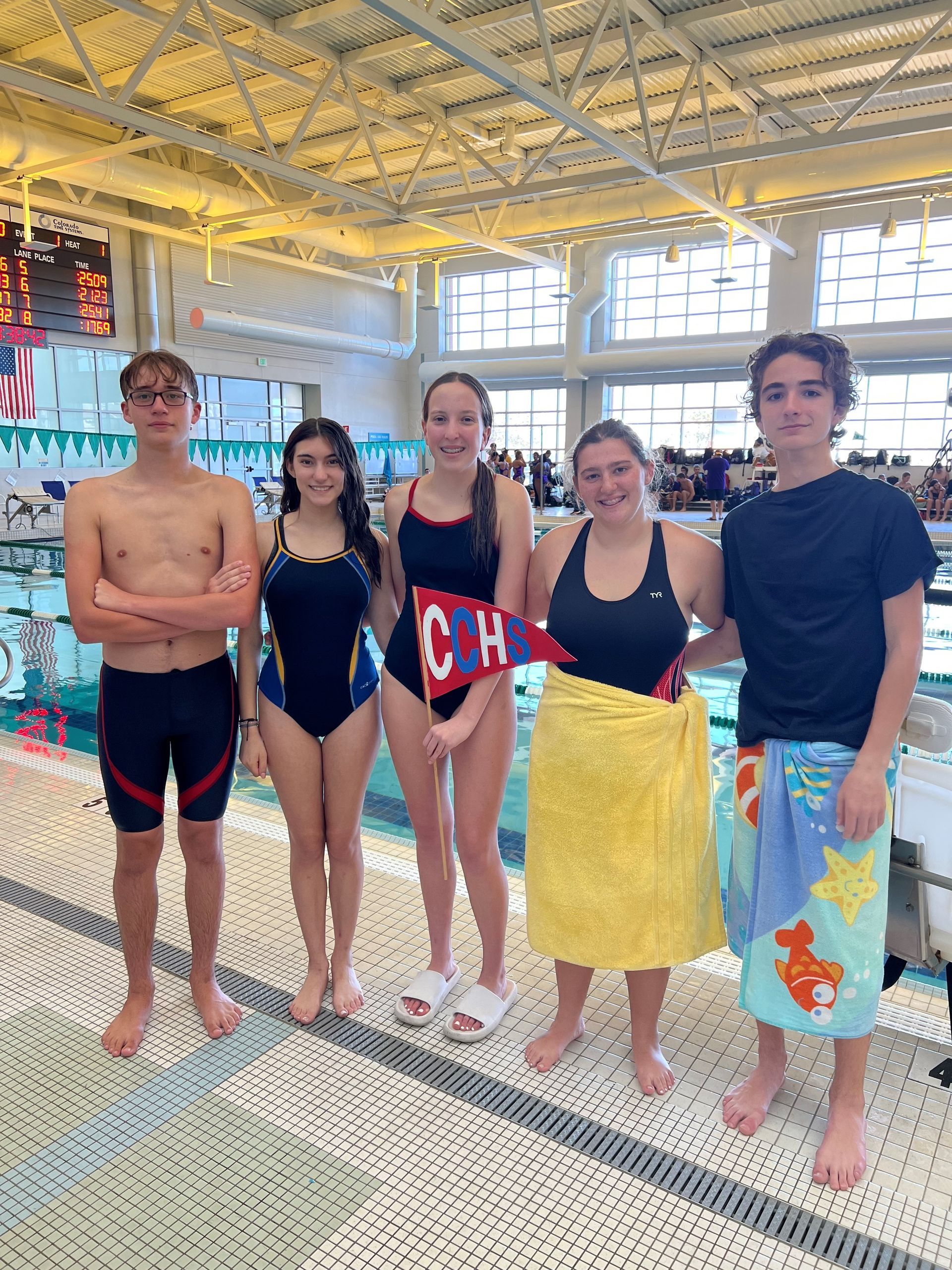 A group of people standing next to a pool holding a sign that says ooh