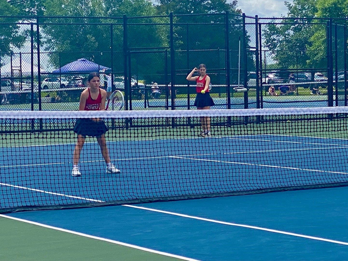 A woman wearing a red shirt that says ' ucsd ' on it is playing tennis