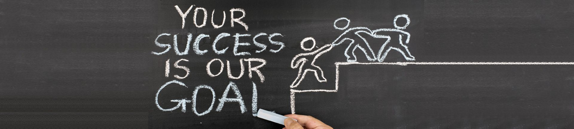 A person is writing on a blackboard that says your success is our goal.