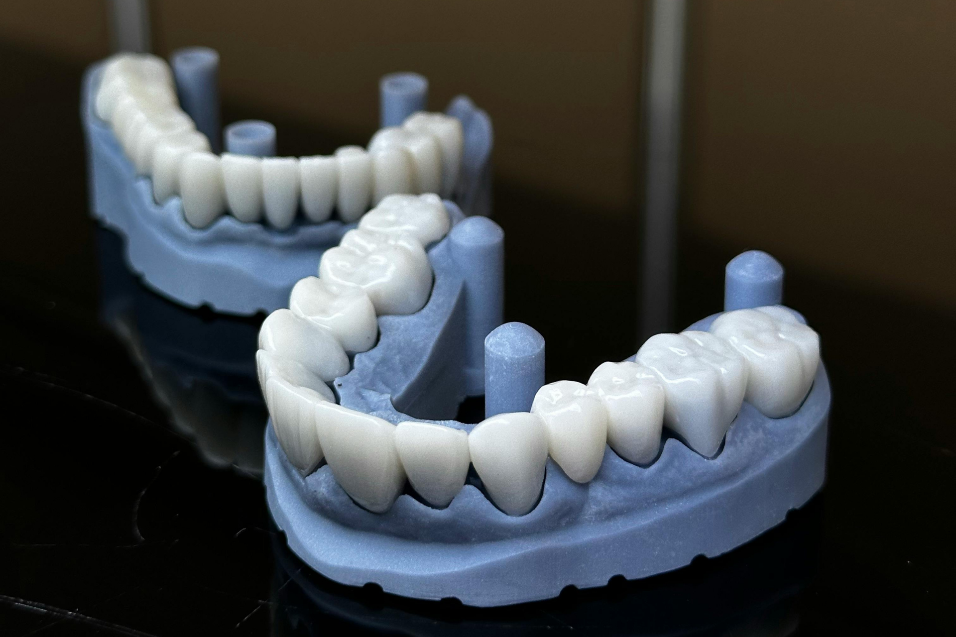 Person in gloves uses a dental drill on a dental mold.