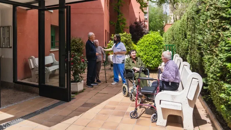 Nurse is taking care of elderly people, helping them enjoy the fresh air and sunshine in the garden of a nursing home