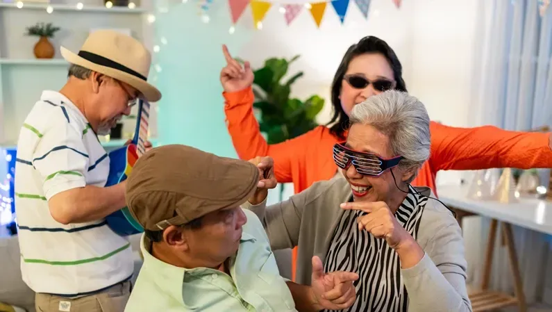 Group of people dancing and celebrating indoors with party decorations.