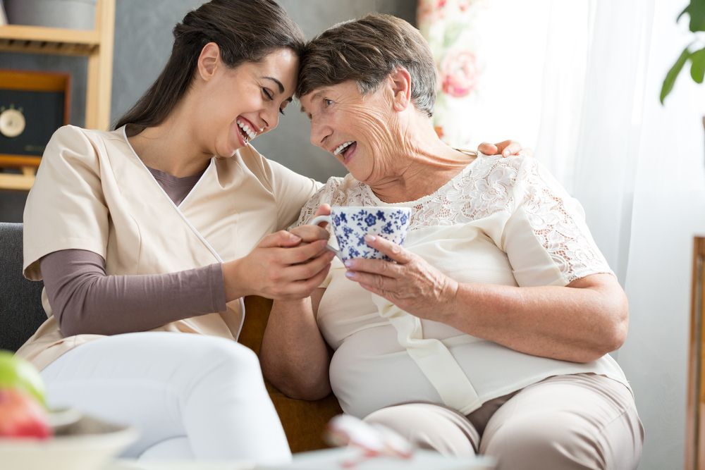 Two women laughing together at a funny joke during afternoon tea break in retirement home