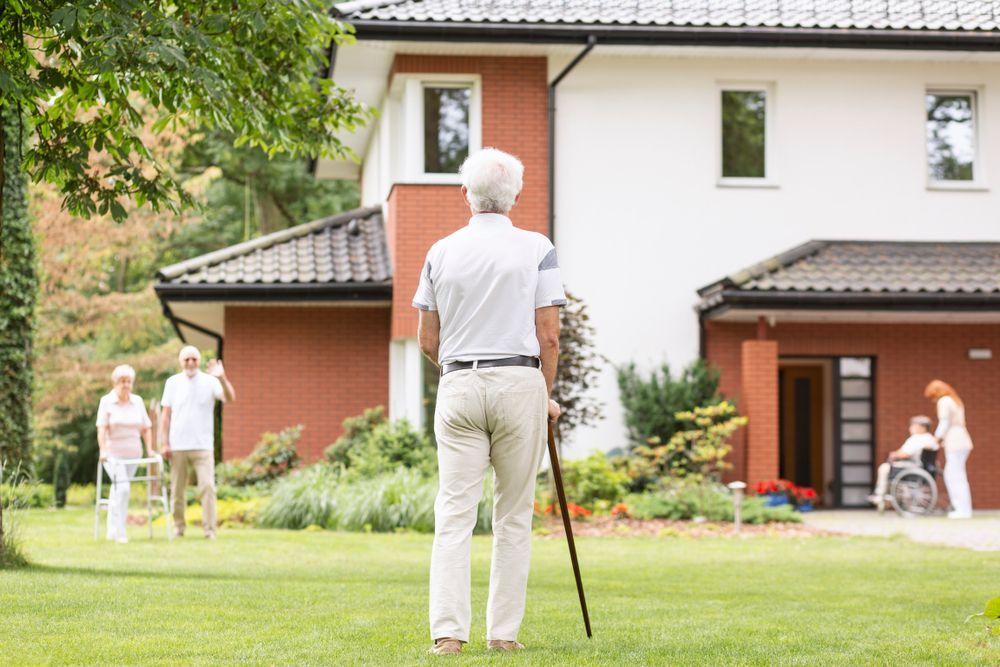 A back of a gray-haired senior man with a cane