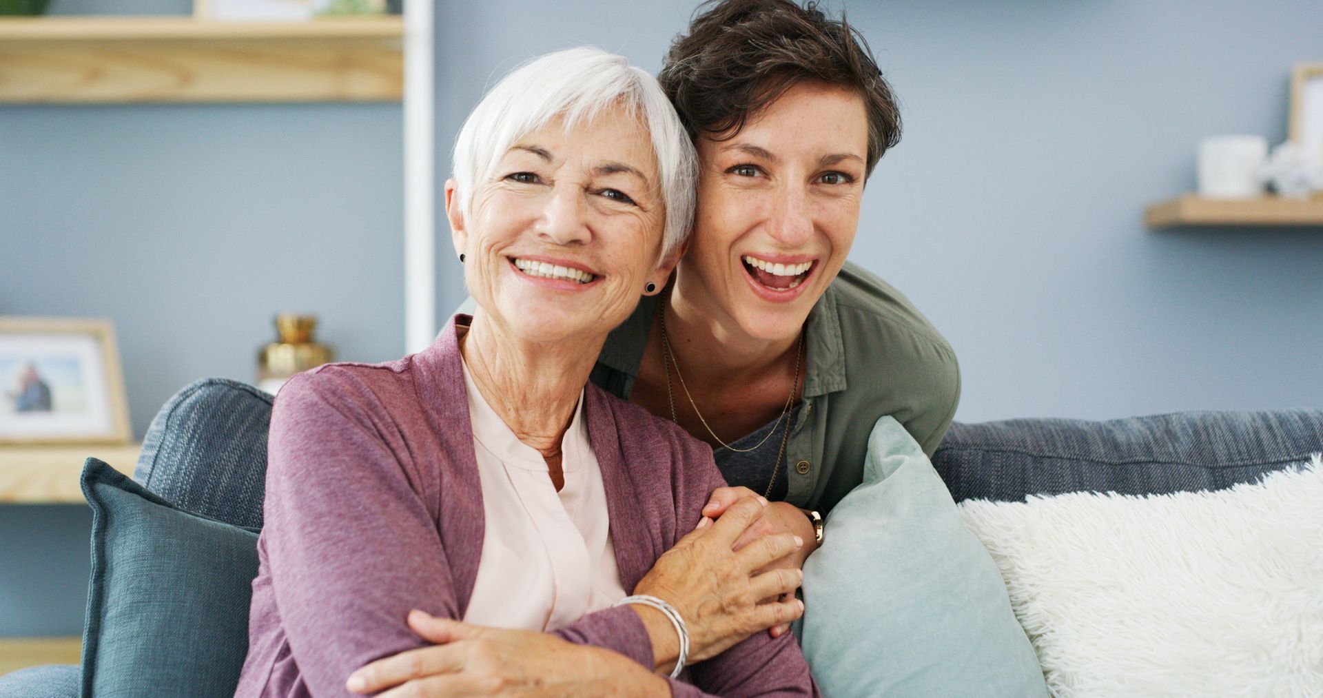 Smiling older woman and younger woman on a couch.