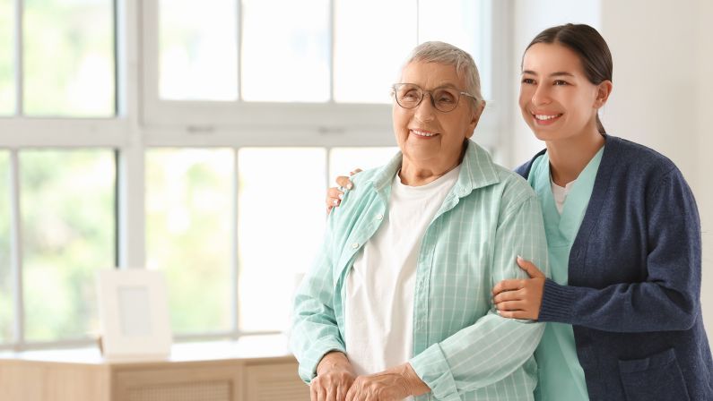 Female caregiver hugging happy senior woman at home