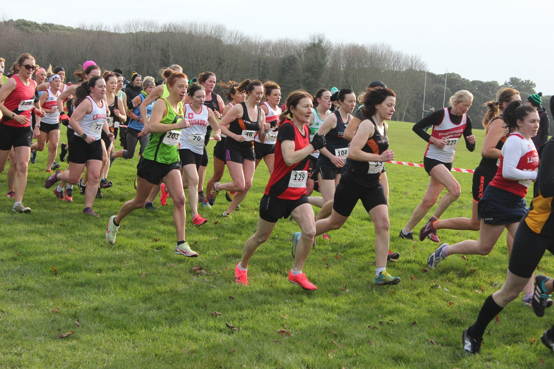 A group of women are running on a grassy field.