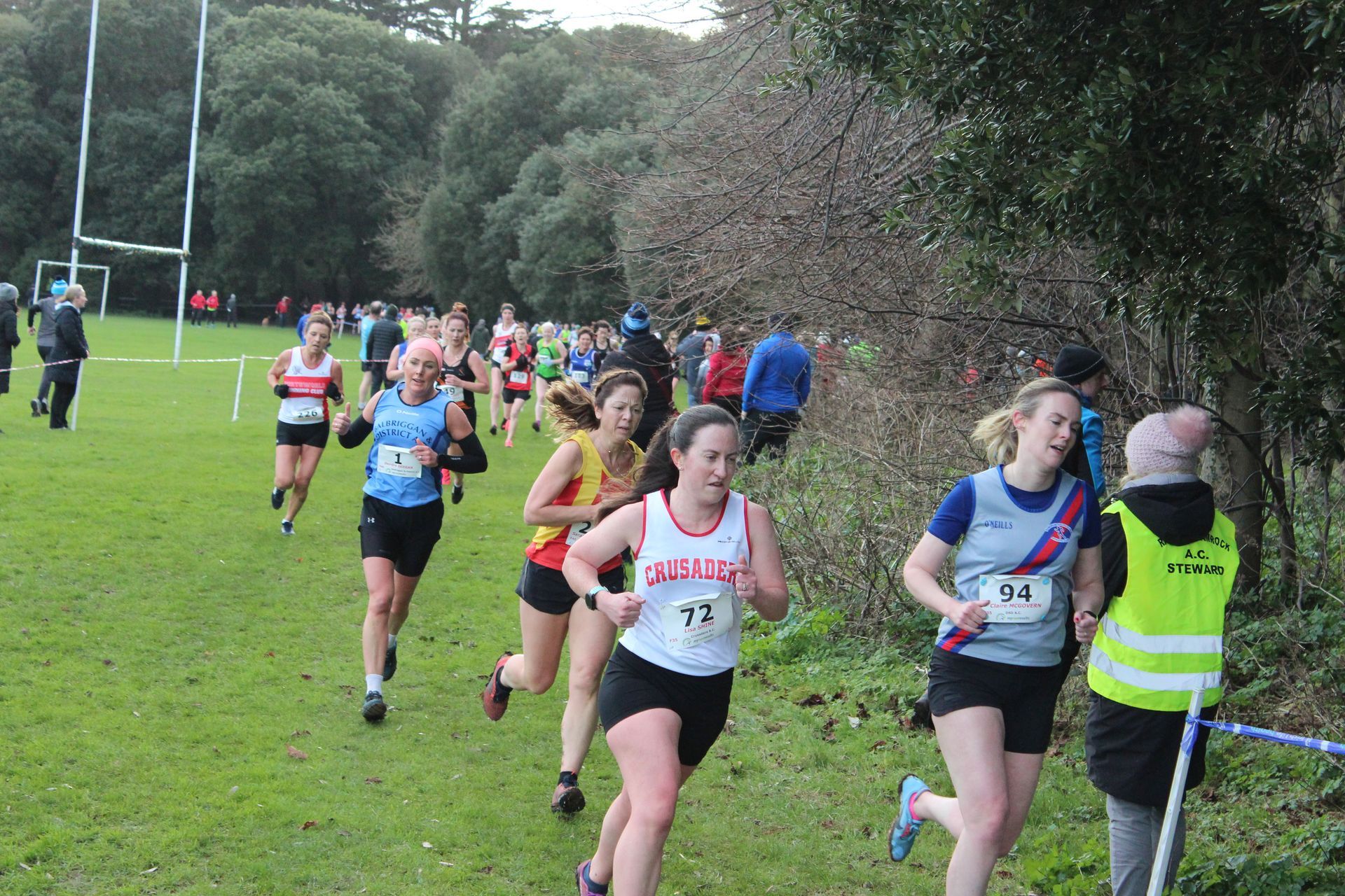 A group of women are running on a grassy field.