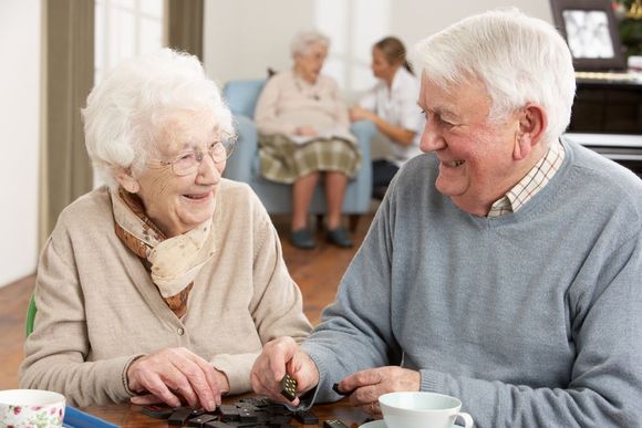 an elderly couple is sitting at a table playing a game .