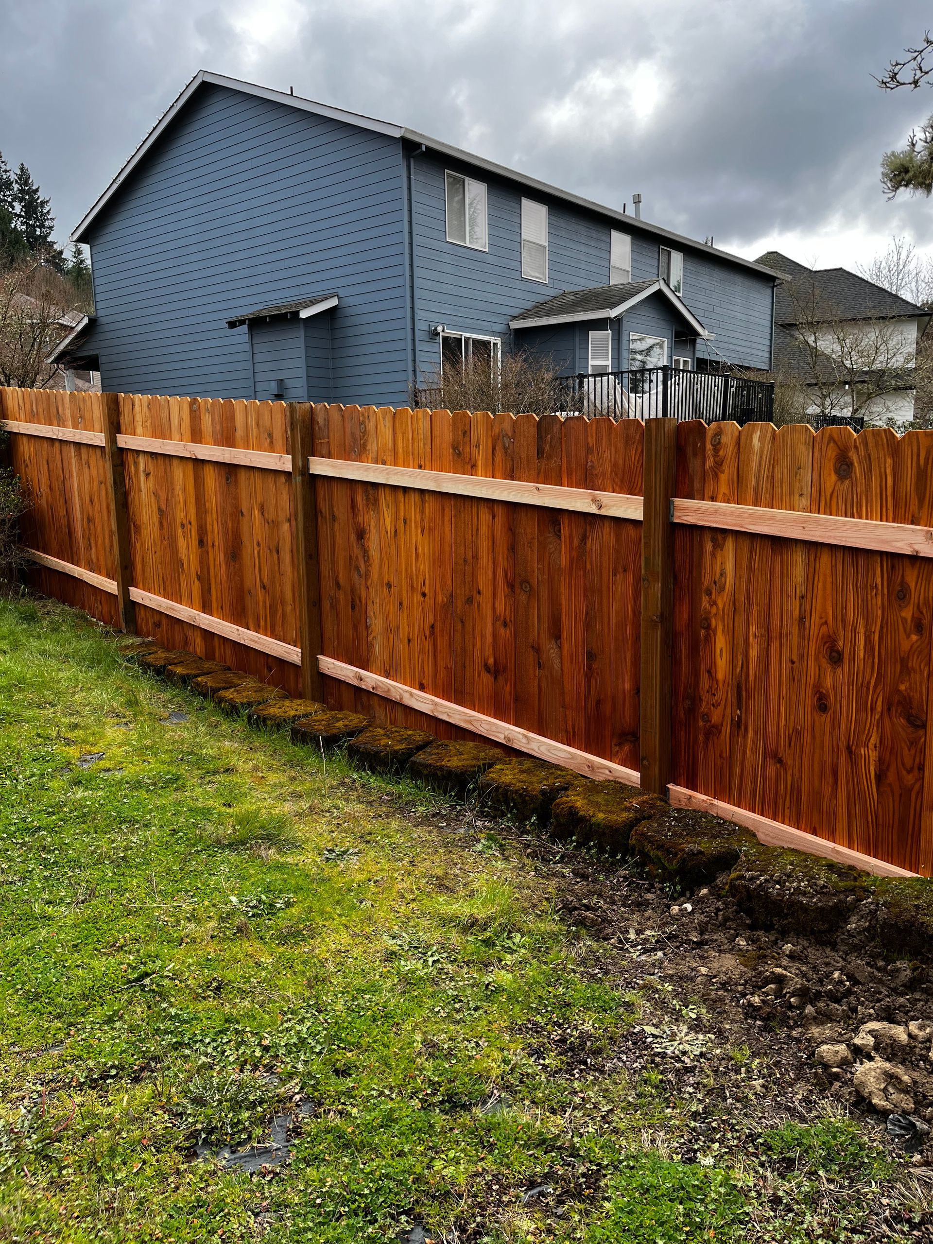A wooden fence is in the backyard of a house.