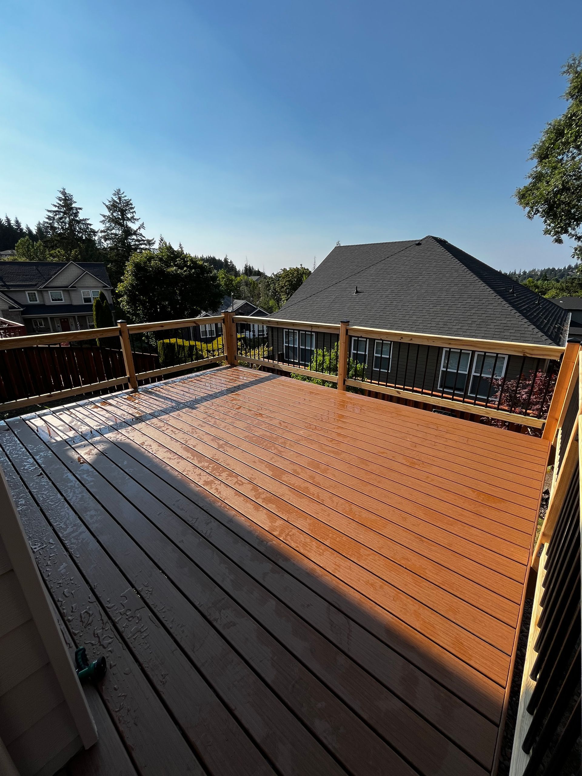 A wooden deck with a wooden railing overlooking a house