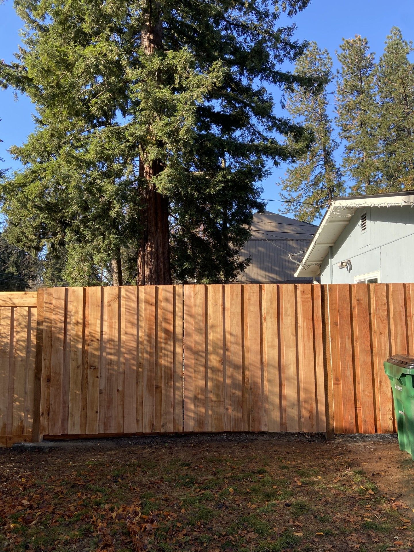 A wooden fence is in the backyard of a house.