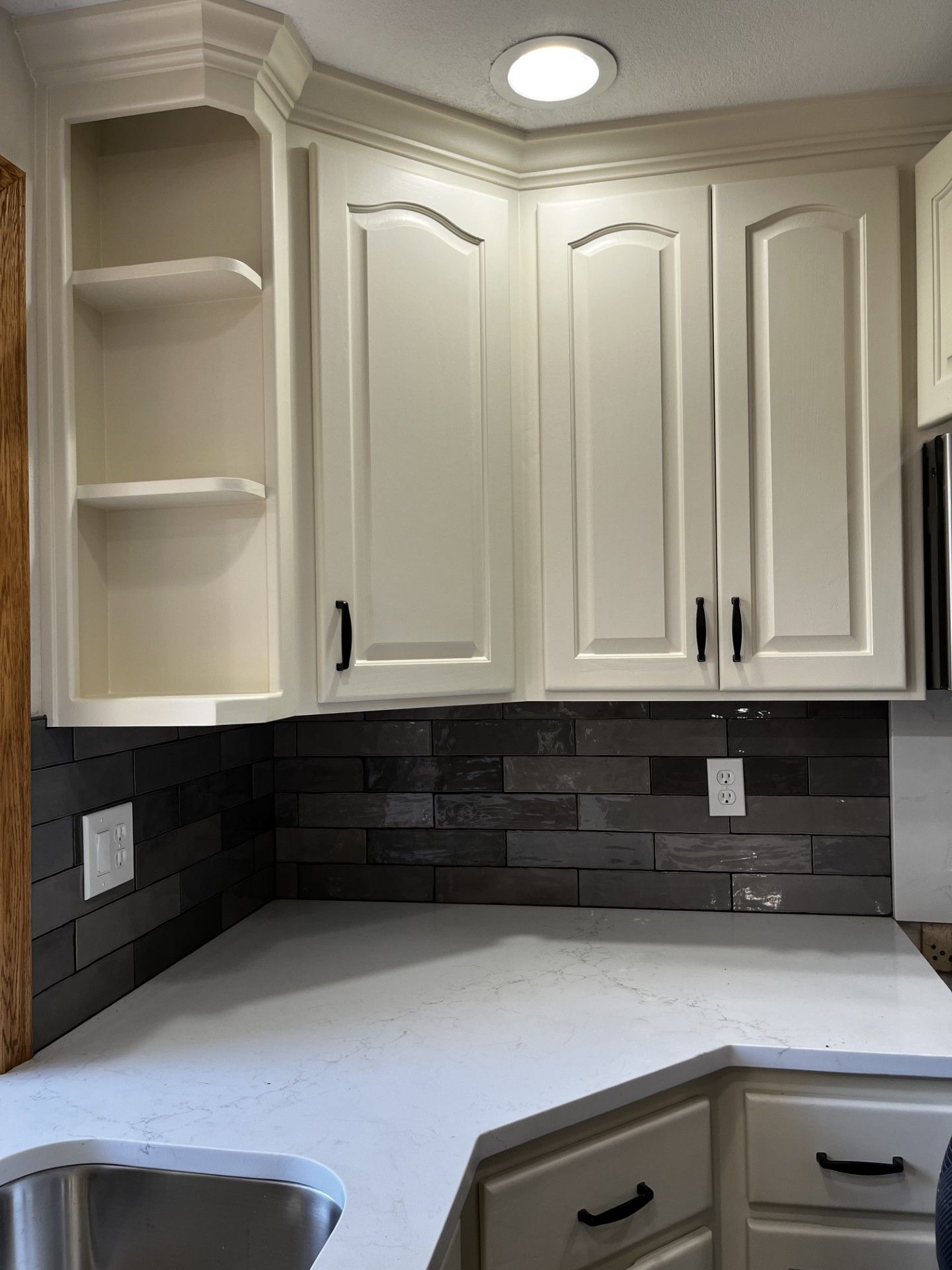 A kitchen with white cabinets , a sink , and a microwave.